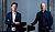 Two men in business attire stand side by side, each with a confident posture, against a neutral background with geometric structures.